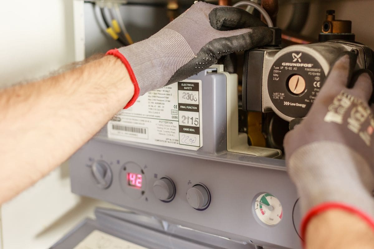 Heating engineer carefully working on the internal components of a gas boiler
